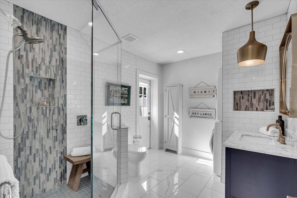 Exceptional tiled bath with heated towel warmer and entrance to the back yard with laundry