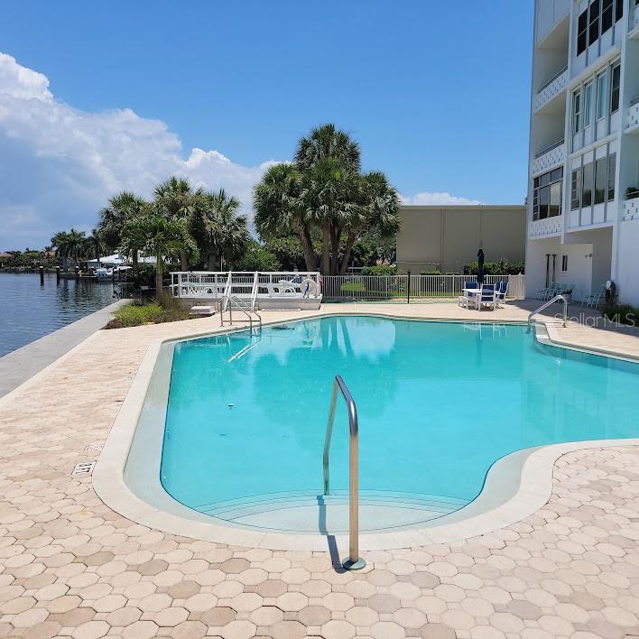 Beyond the pool area is a grill, tables to enjoy a meal with an umbrella for shade, and a shuffleboard court.