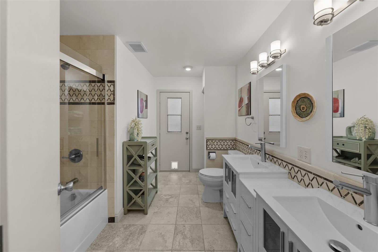 Updated bathroom with dual sinks and access to the pool,  adjacent to second bedroom/guest suite