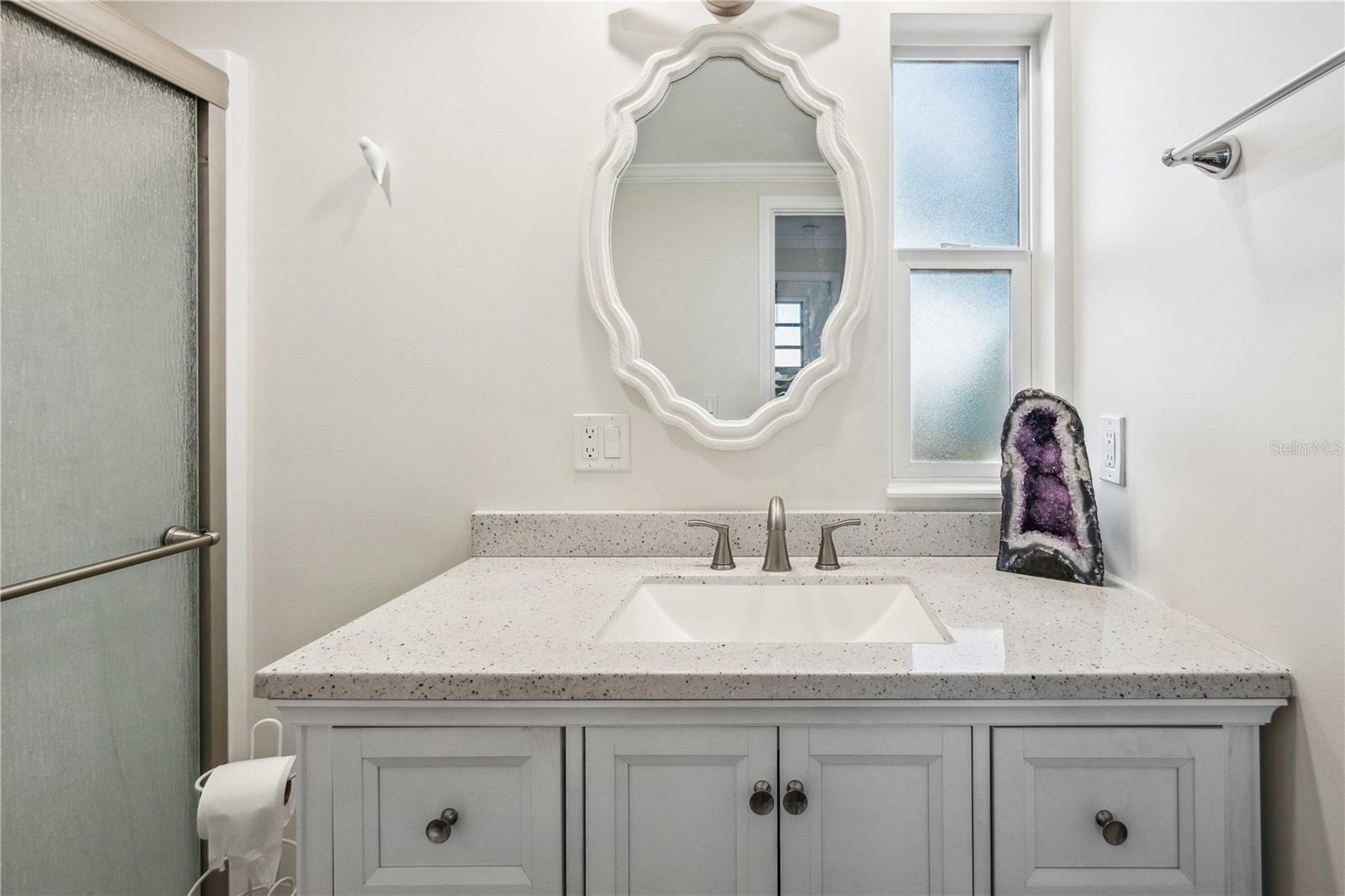 Primary bathroom has step-in shower and stone countertop.