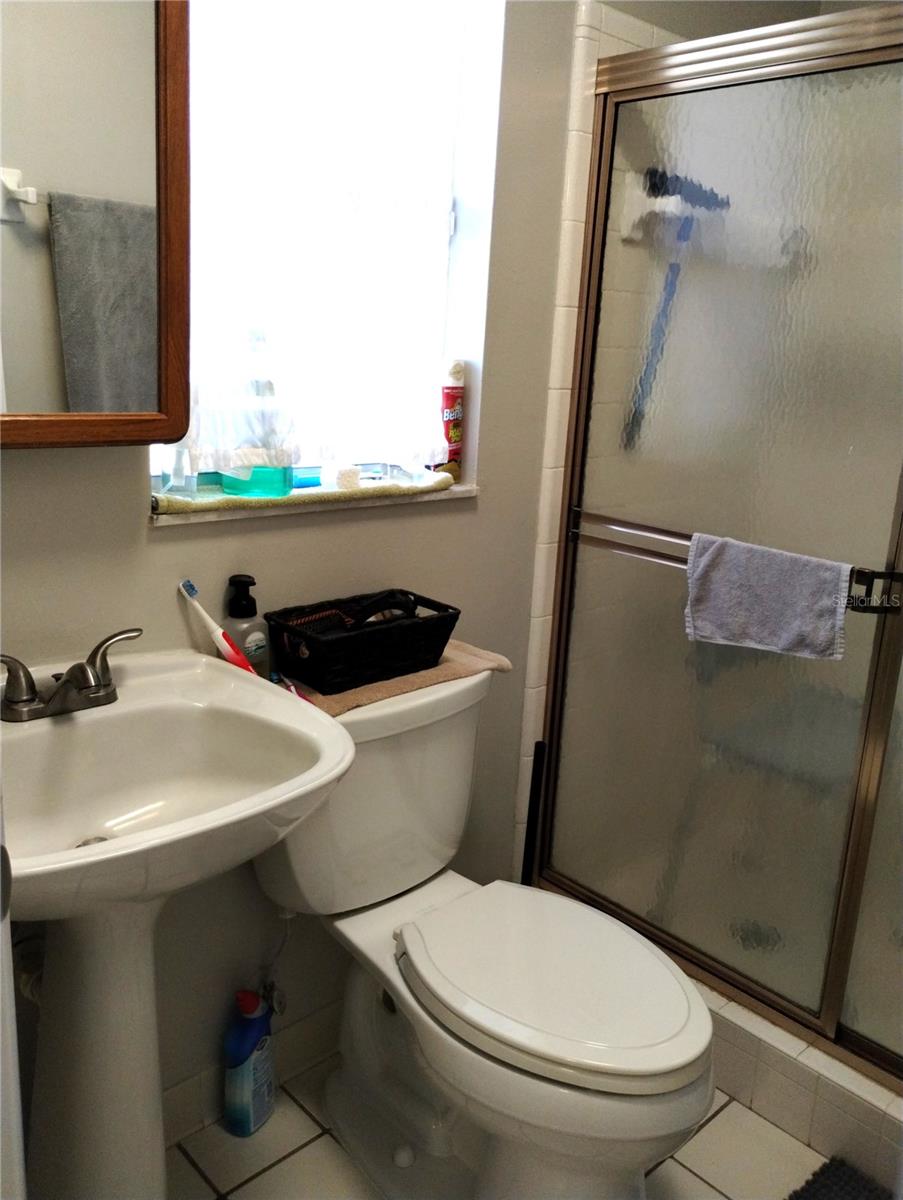 En suite bathroom in primary bedroom has shower with no tub.