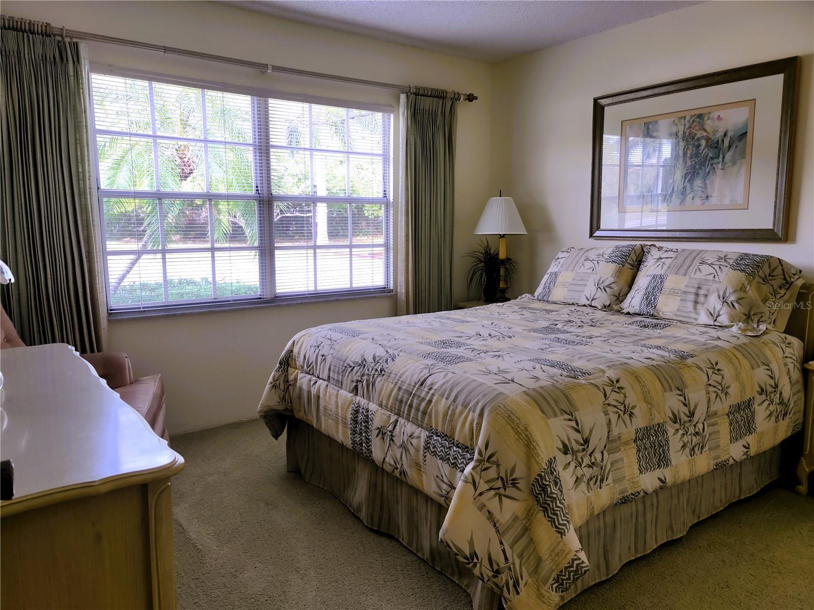 Bright cheerful guest bedroom comfortably accommodates a queen size bed.