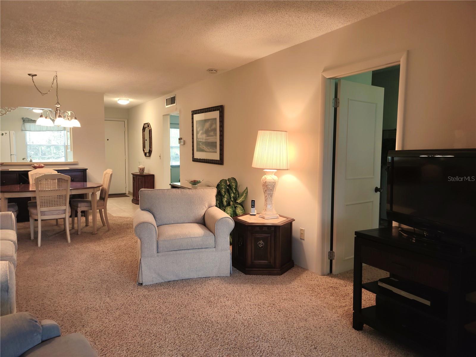 View from bonus room thru living area to entry. Primary ensuite bedroom quarters on lower right.