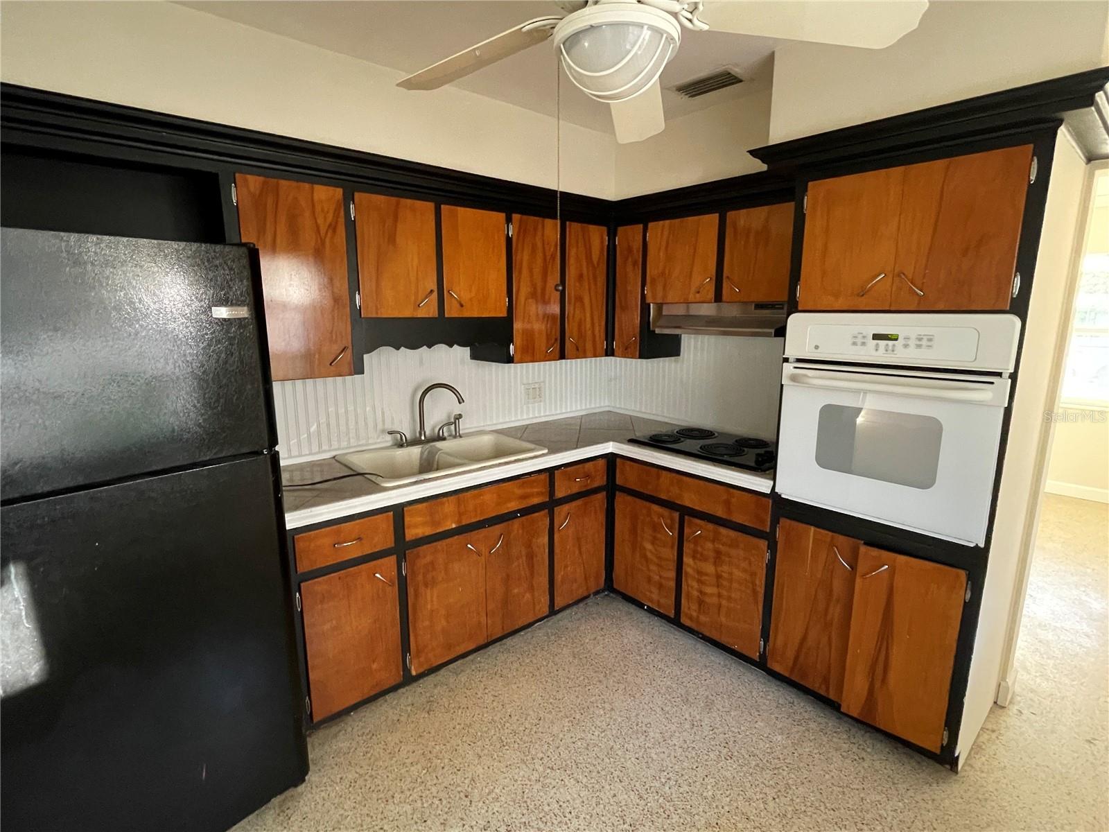 Dramatic black and woodtoned  cabinets. Opening to right of wall oven leads to living room.