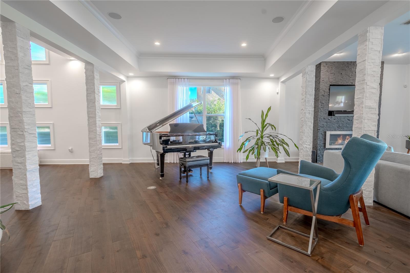 The living room is highlighted by a striking picture window that floods the space with natural light, beautifully framed by elegant stone columns that add a touch of sophistication and architectural charm.