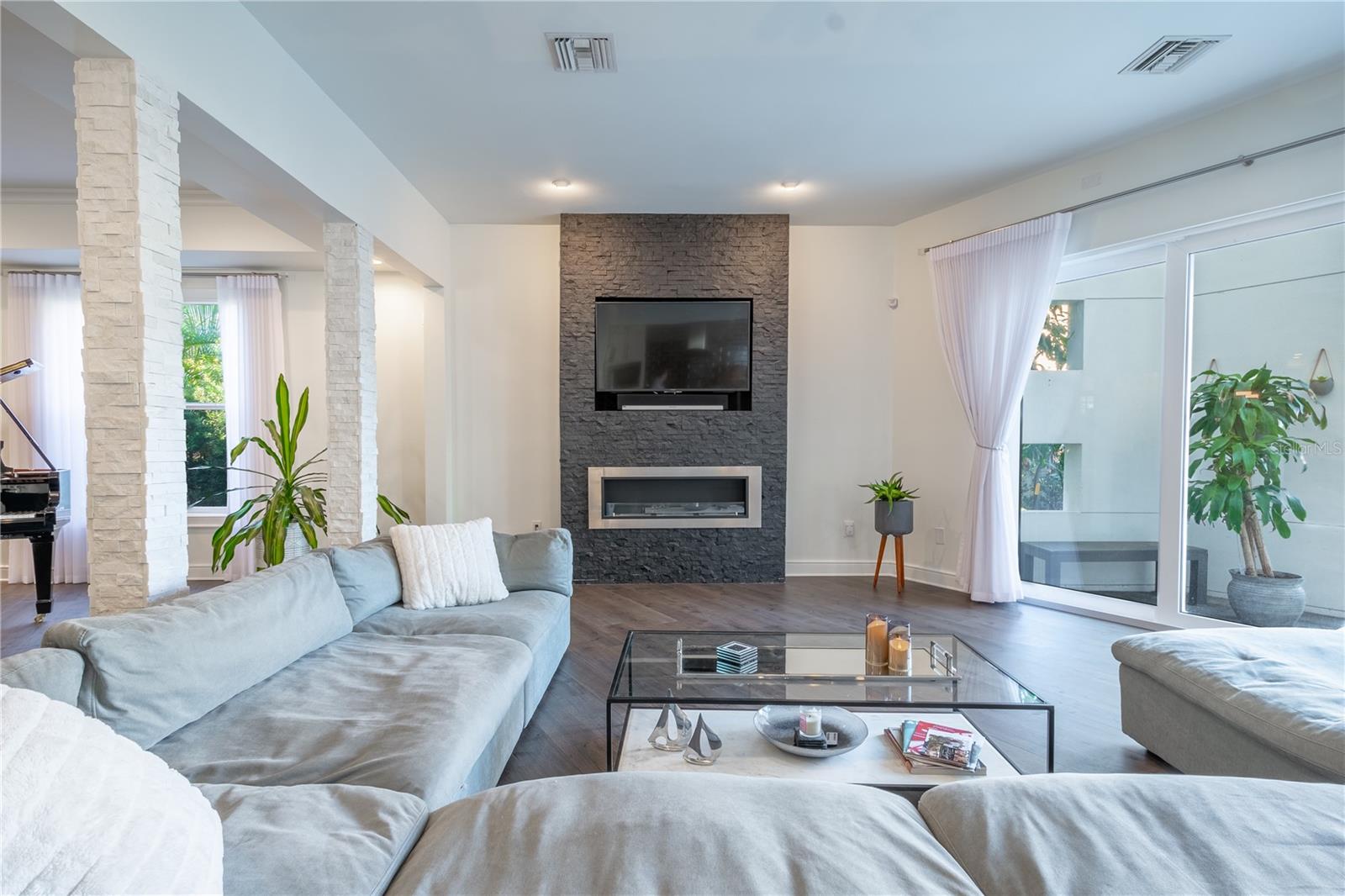 The family room features a sleek stacked stone fireplace with a bioethanol-burning design, offering a clean, eco-friendly flame that adds warmth and modern elegance to the space.