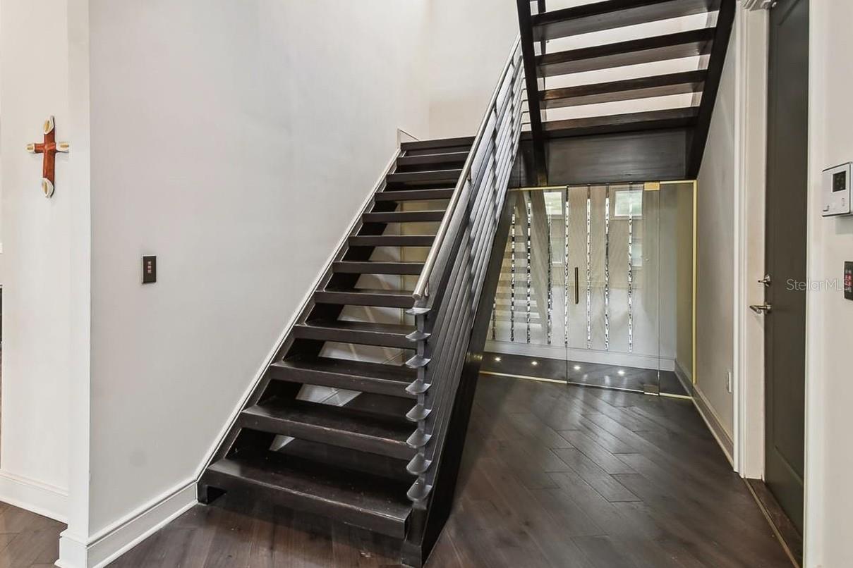 Beneath the stairs is a glass enclosed wine room.