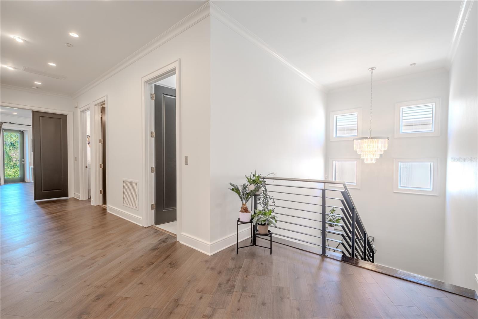 The second floor hallway, features wood flooring, crown molding and recessed lighting.