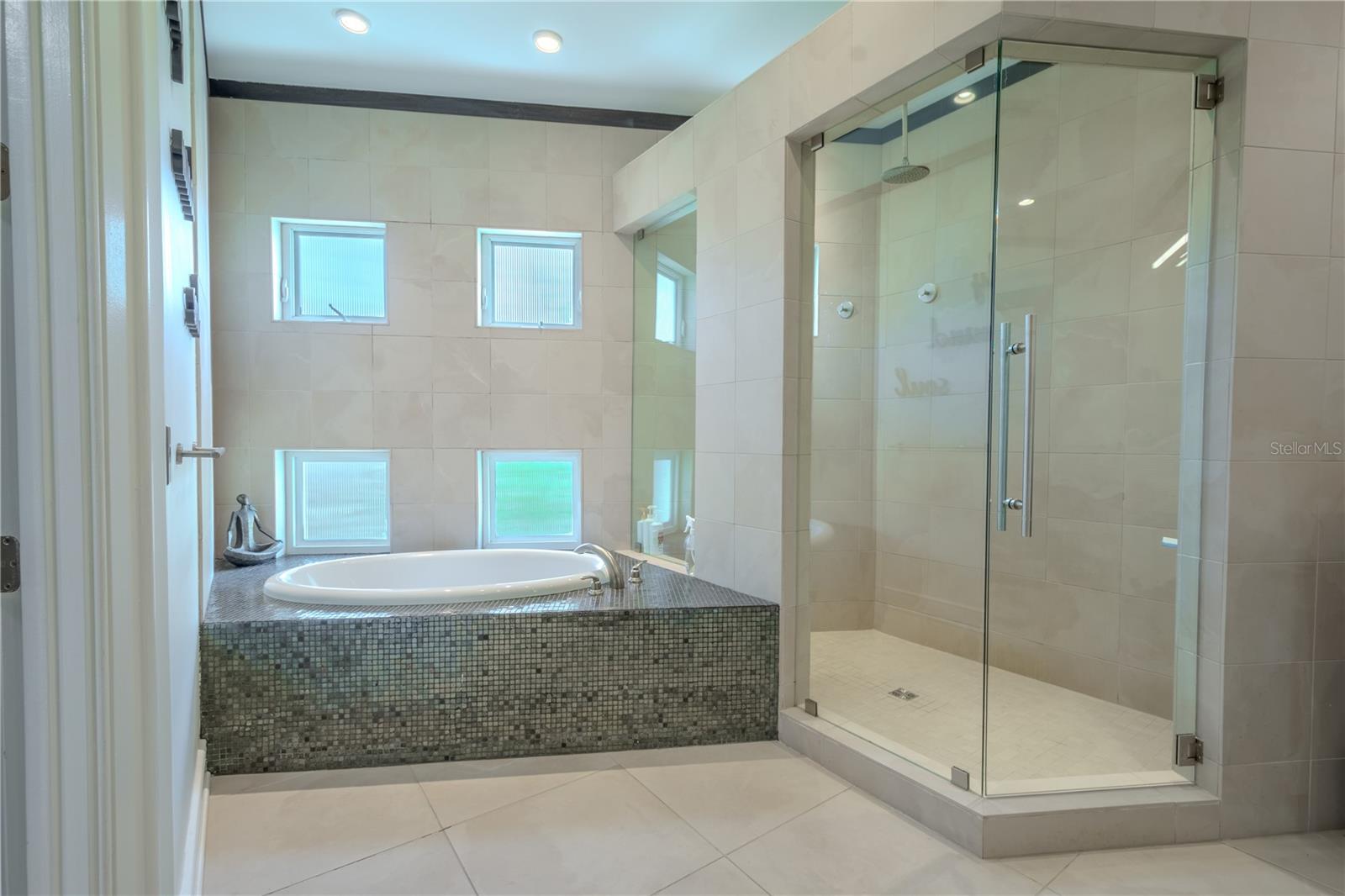 Indulge in luxury: the primary ensuite features a spacious walk-in shower with multiple shower heads and a jetted soaking tub.