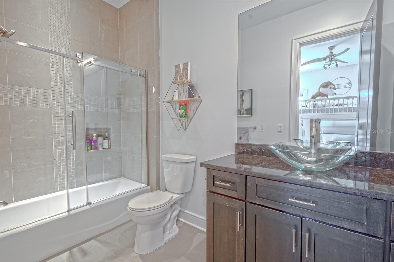 The 4th bathroom (an ensuite in the 5th bedroom) features a mirrored wood vanity with vessel sink, and a tiled tub with shower.