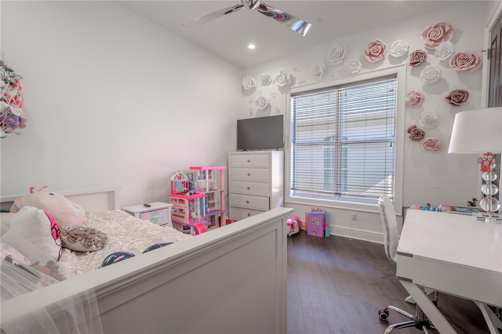 The 6th bedroom features a modern ceiling fan, neutral tones, laminate flooring and a walk-in closet.