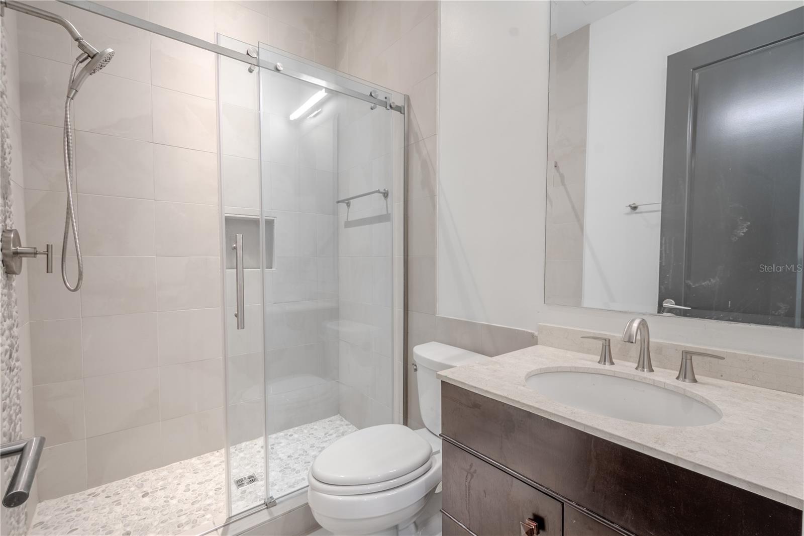 The 3rd bathroom features a mirrored vanity with storage and a walk-in shower.