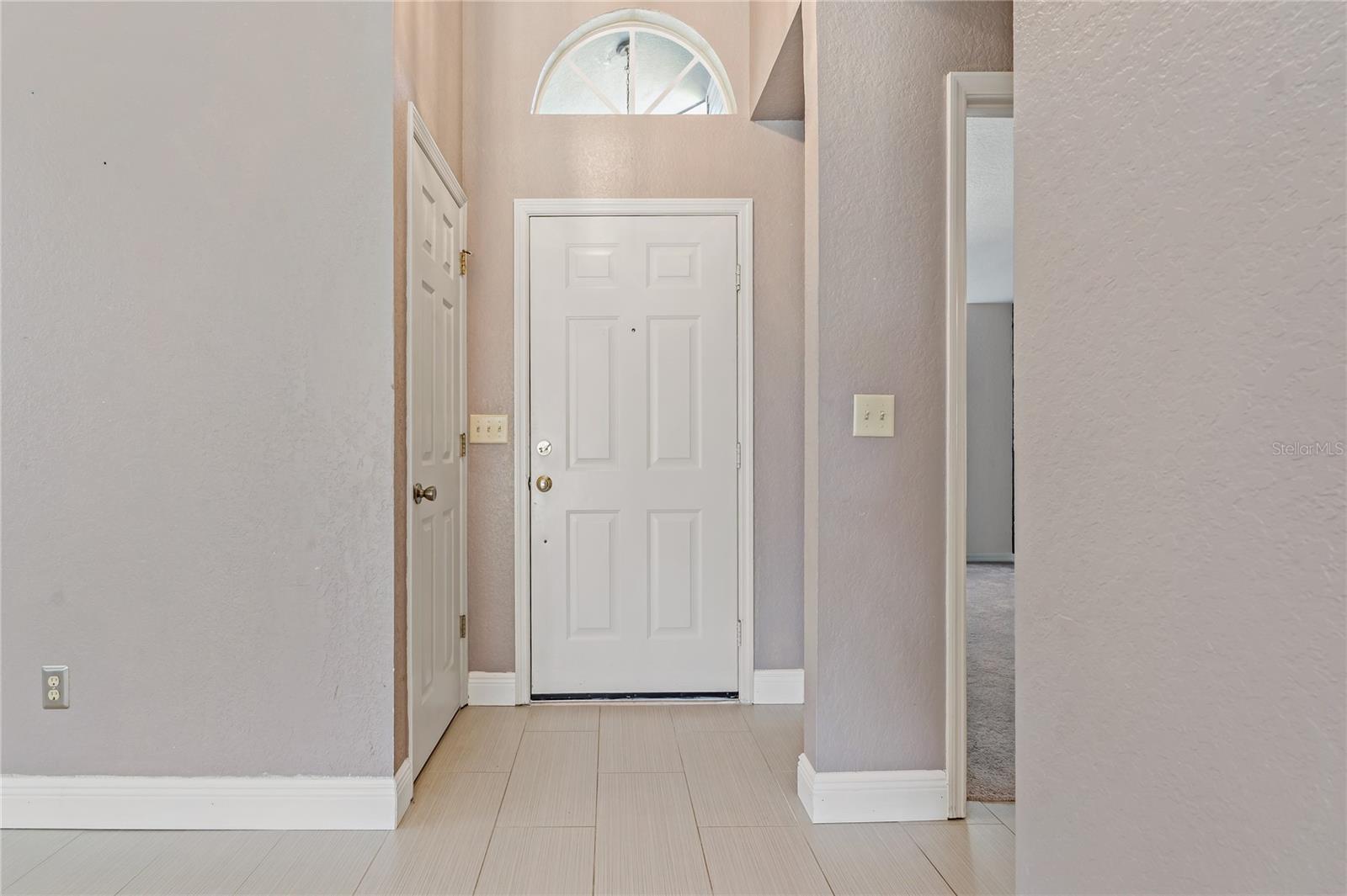 Front Door Foyer with Coat Closet on Left and Transom Half Round Window