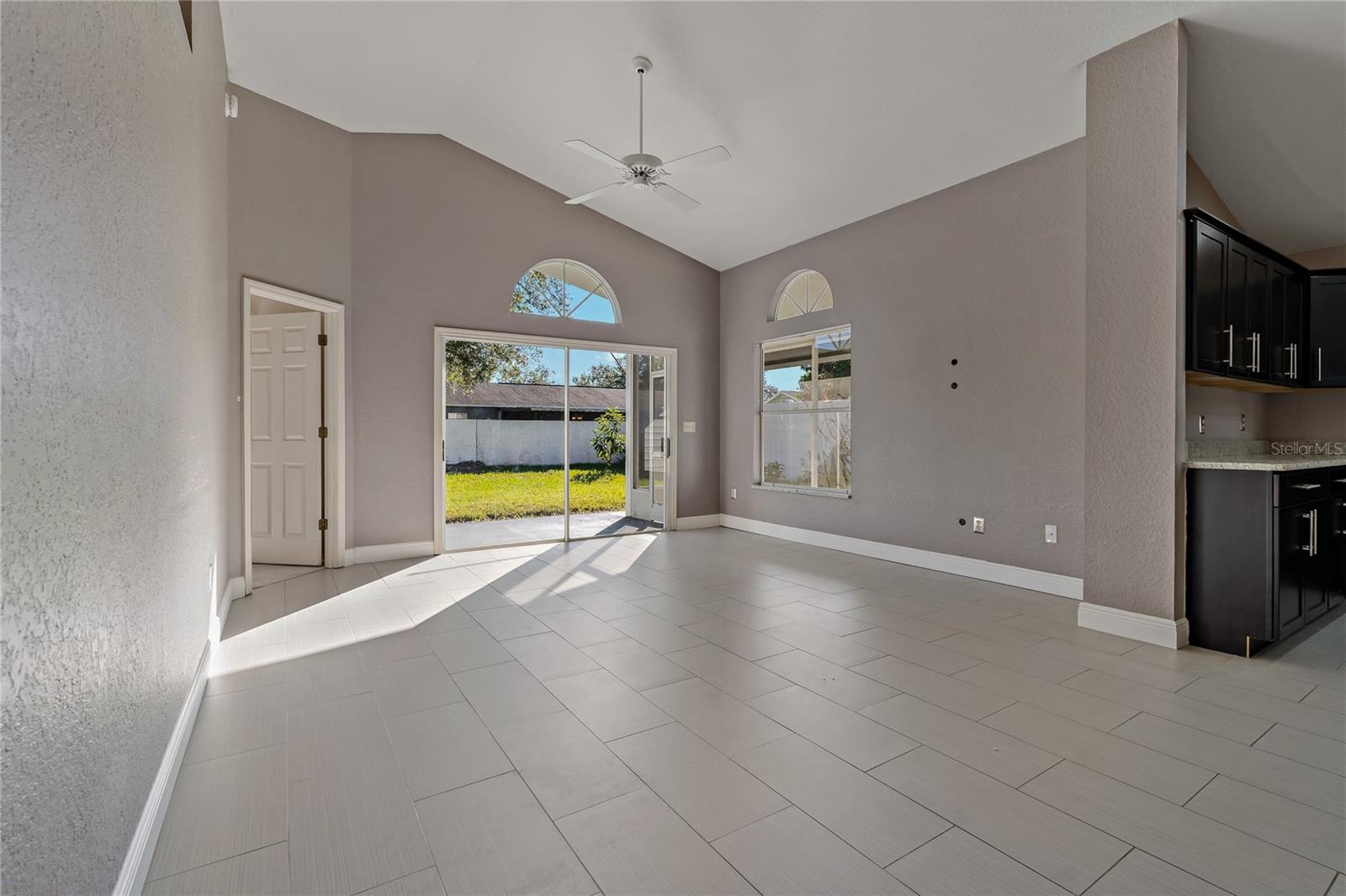 Living Room with two Transom Half Round Windows, Sliding Doors to Covered Lanai and Ceiling Fan