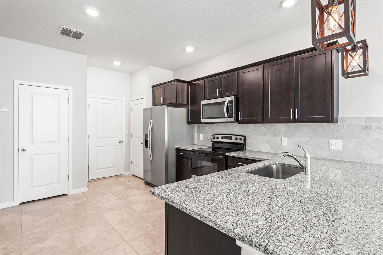 Stone countertops, cabinet pulls, & pantry + easy access to the one car garage.