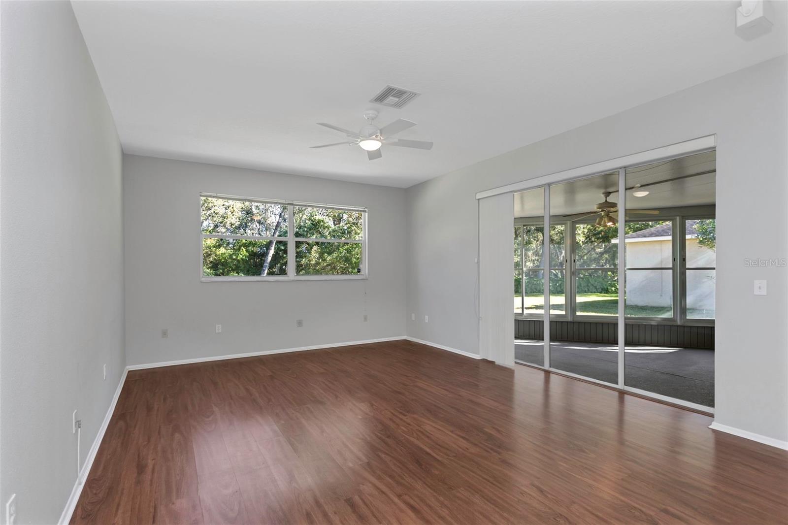 Family room with laminate flooring and sliders to spacious enclosed lanai.