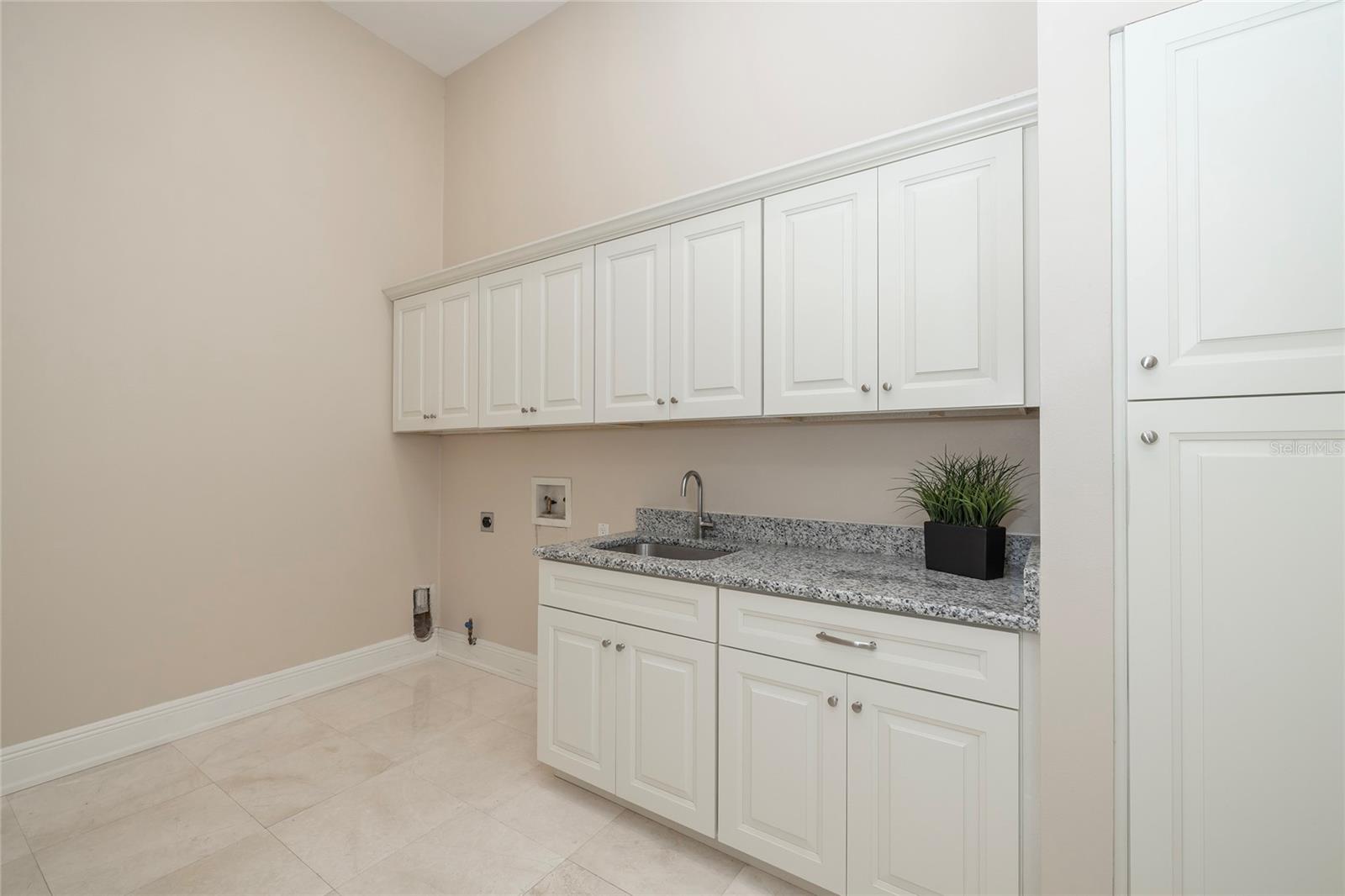 First floor laundry room. Wood cabinets and granite top