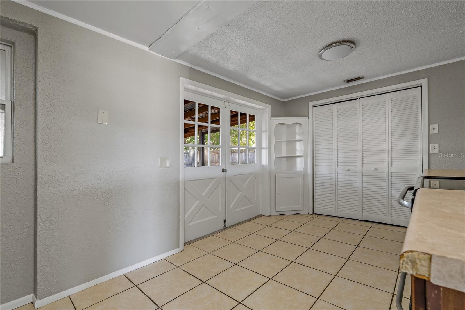 SPACIOUS KITCHEN WITH BUILT IN LAUNDRY CLOSET AND FRENCH DOORS LEADING TO SCREENED IN LANAI