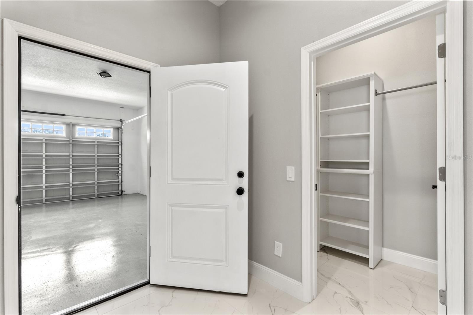 garage view going into house and large storage area off the hallway, opposite the laundry room