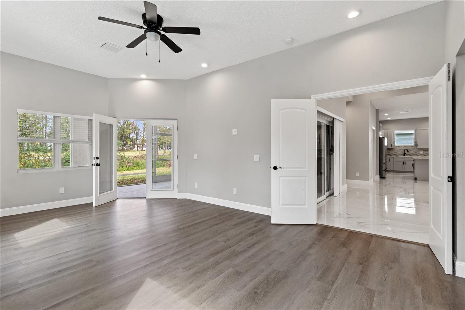 Primary bedroom - view 3 french doors leading onto the screened patio -view of golf course