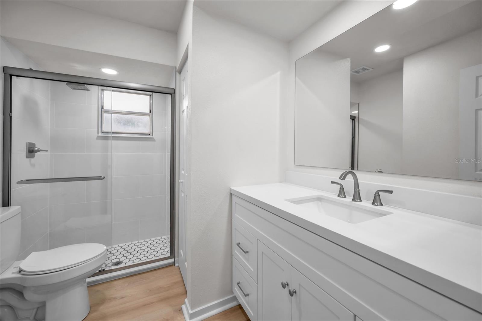 Newly Renovated En Suite Bathroom Boasting Walk-in Shower and Marble Sink and Countertop