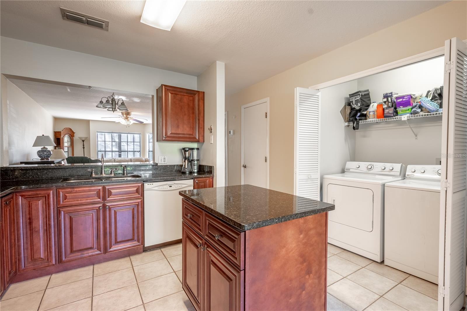 A laundry closet with washer and dryer and overhead shelving is located in the litchen.