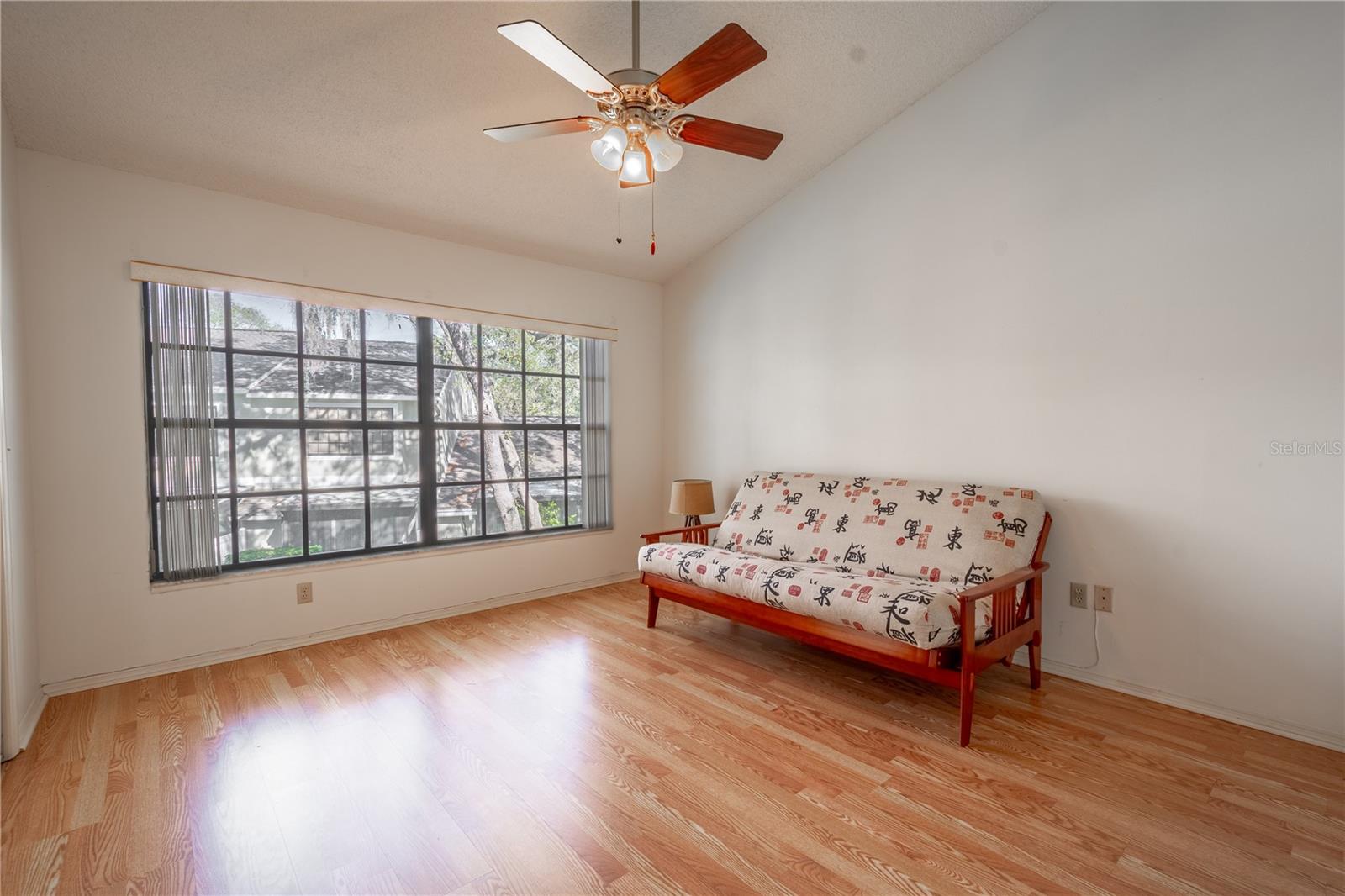 The 2nd bedroom features a large picture window, wood laminate flooring, vaulted ceiling and a ceiling fan with light kit.