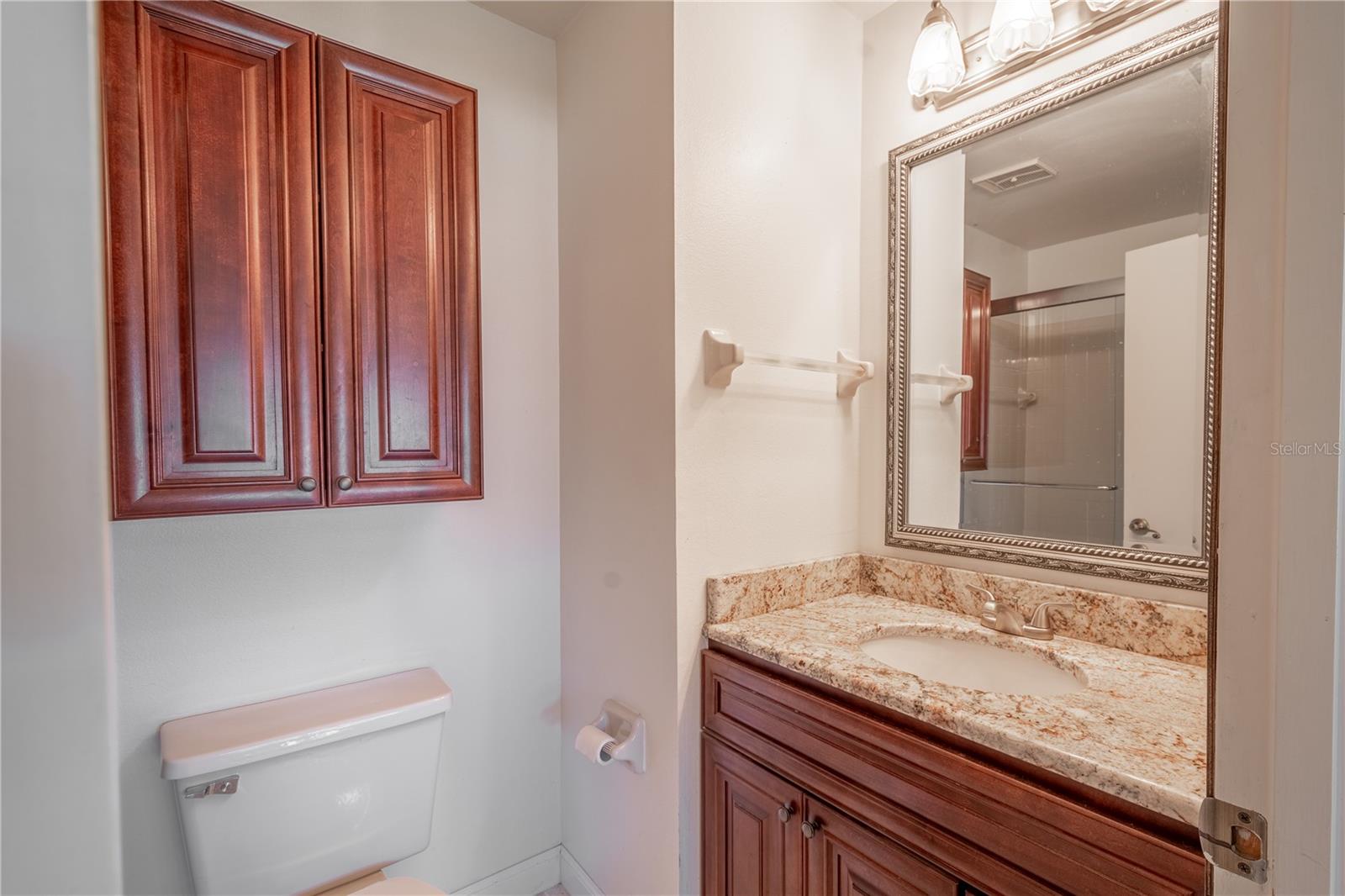 The 2nd bathroom (an ensuite) with wood cabinets and granite counters and a glass enclosed, walk-in shower.