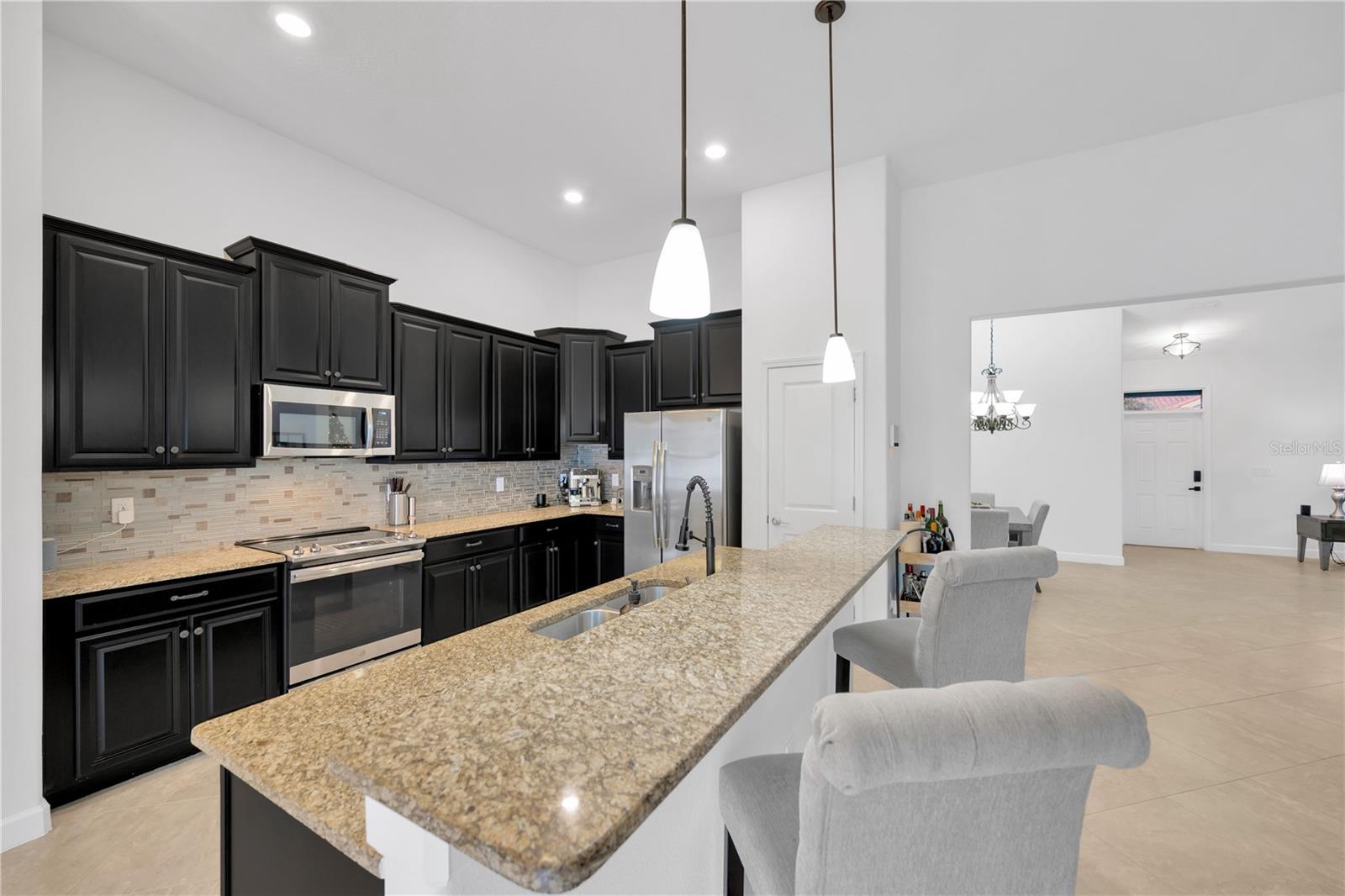 kitchen is gourmet-inspired and has miles of granite counters with an island prep area complete with a double bowl undermount sink, staggered wood cabinets with a stylish tiled backsplash to compliment the sparkling stainless steel appliances.