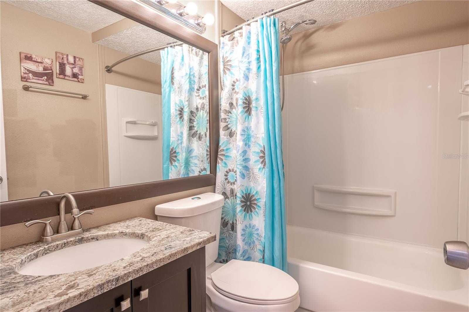 The bathroom features a mirrored vanity with storage, ceramic tile floor and a tiled tub with shower.