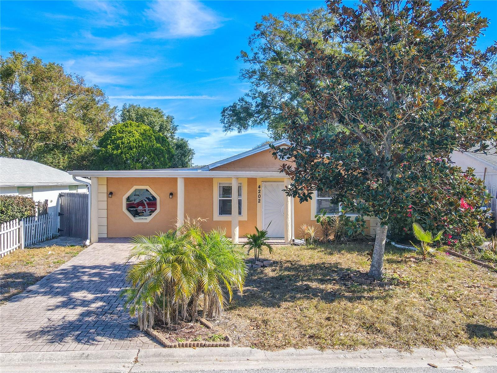 Charming bungalow with covered front entryway and pavered driveway.