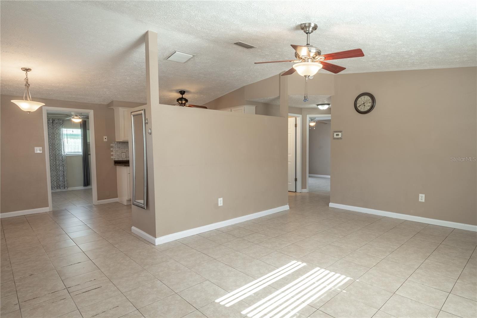 The living room is open to the dining room which also has the same warm tones, ceramic tile floor and pendant light.