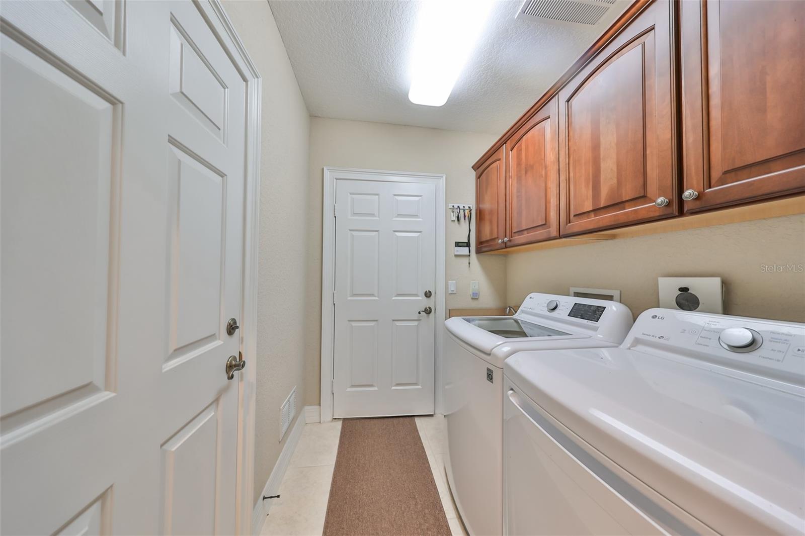 The laundry room is large with a utility sink and beautiful cabinetry for storage.