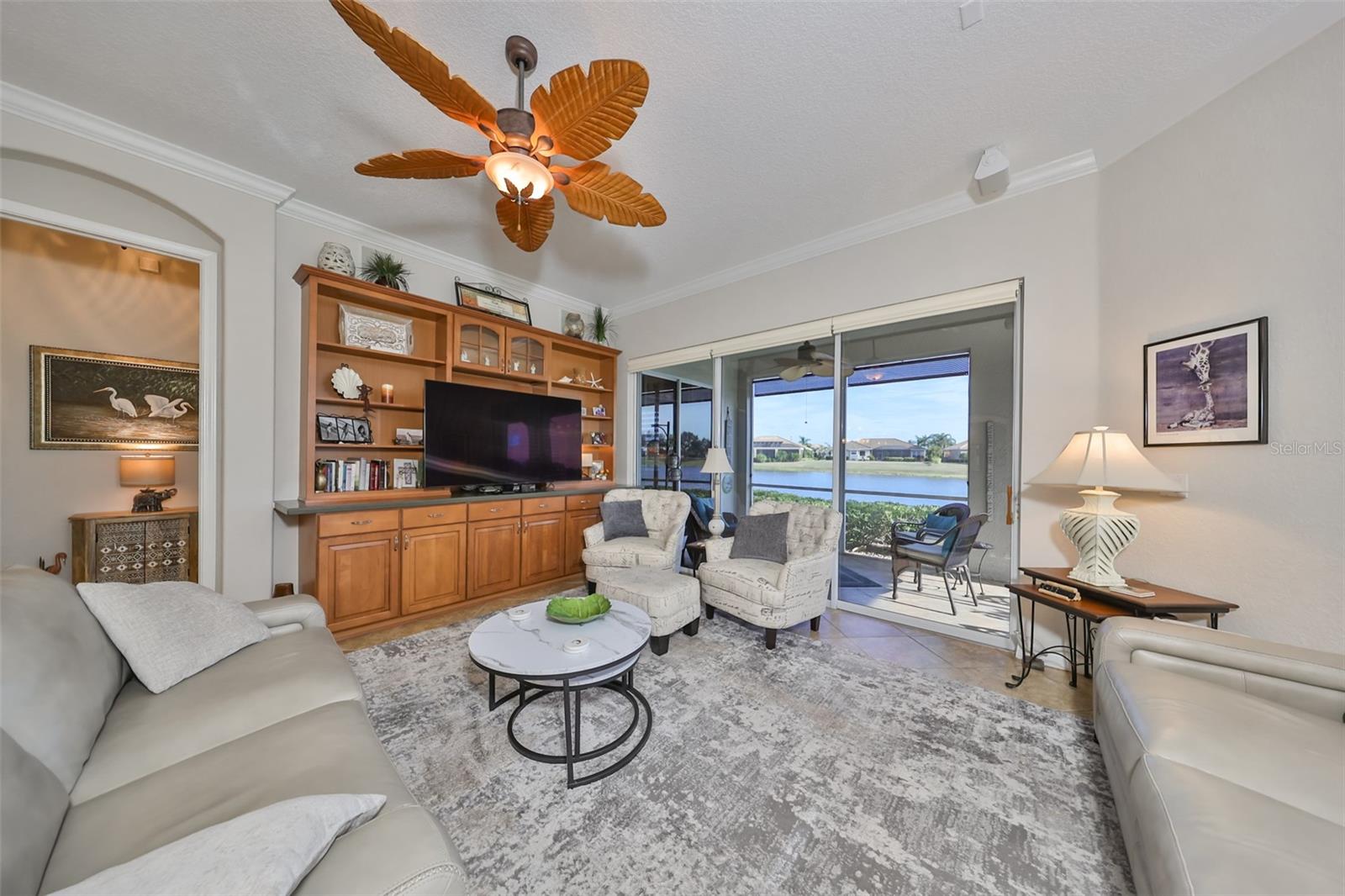 The great room is large with water views and a custom ceiling fan.  Notice the 10-12' ceiling and architectural feature around the door.