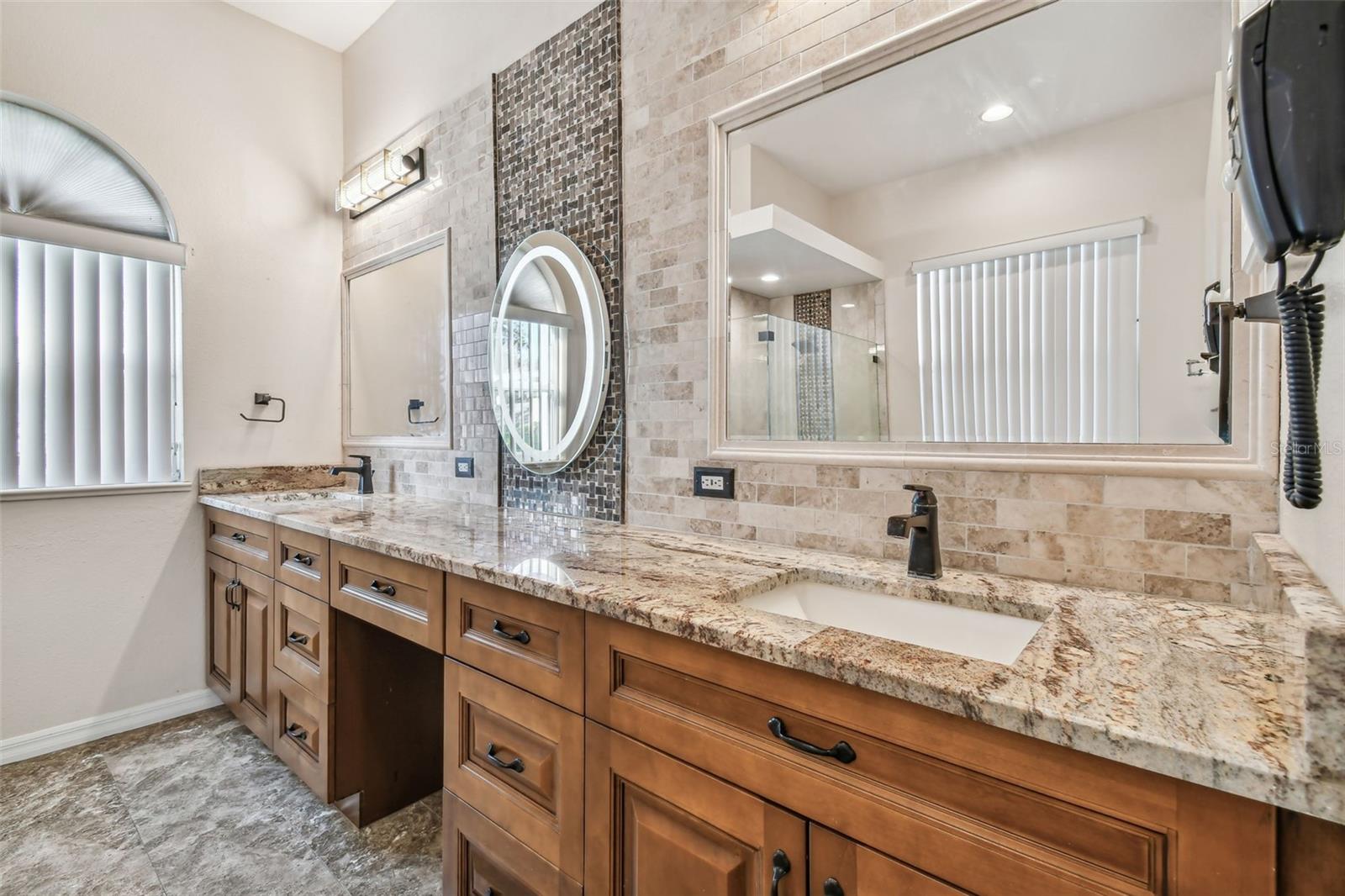 Dual sinks with lots of stone countertops and backsplash make this bathroom a show stopper.