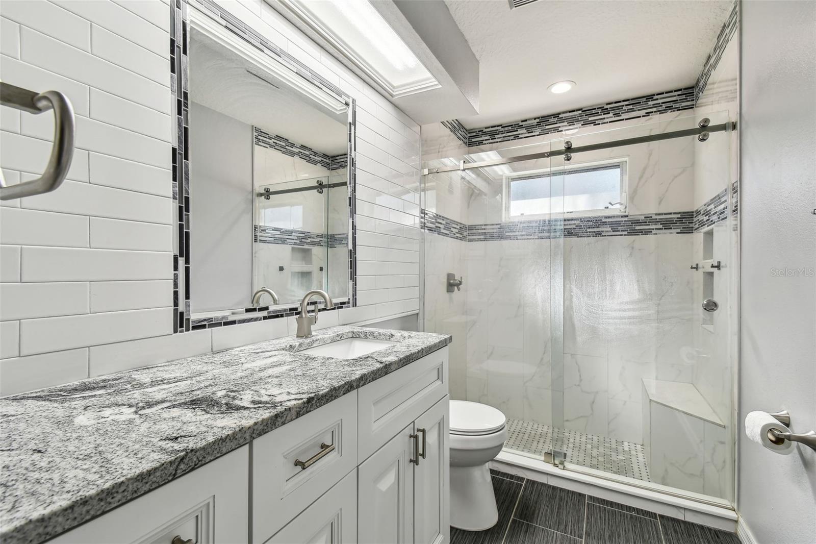 Bathroom 3 is beautifully decorated with stone countertops and tile accents in the walk in shower.