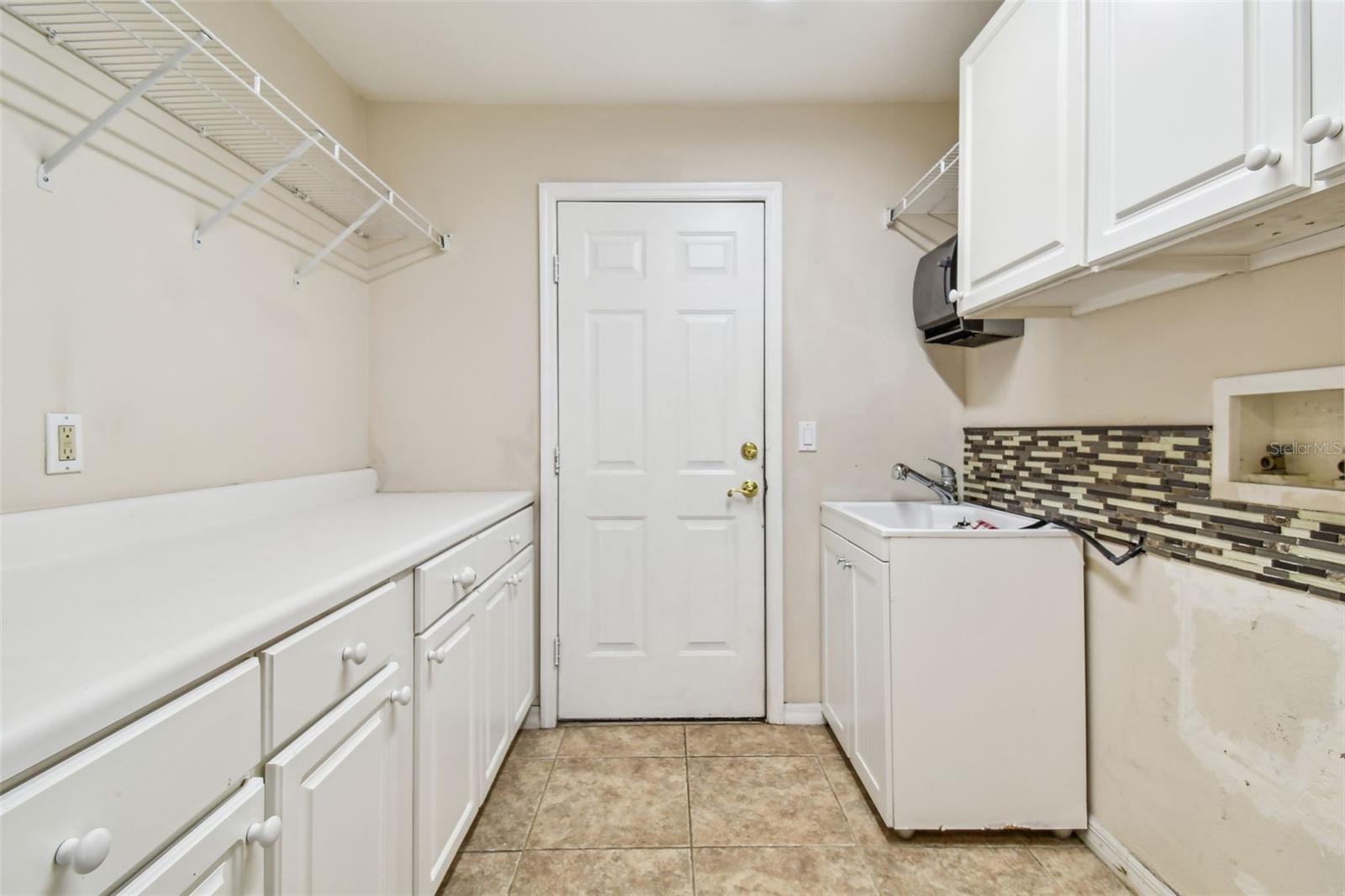 Laundry room with lots of cabinets and a sink.