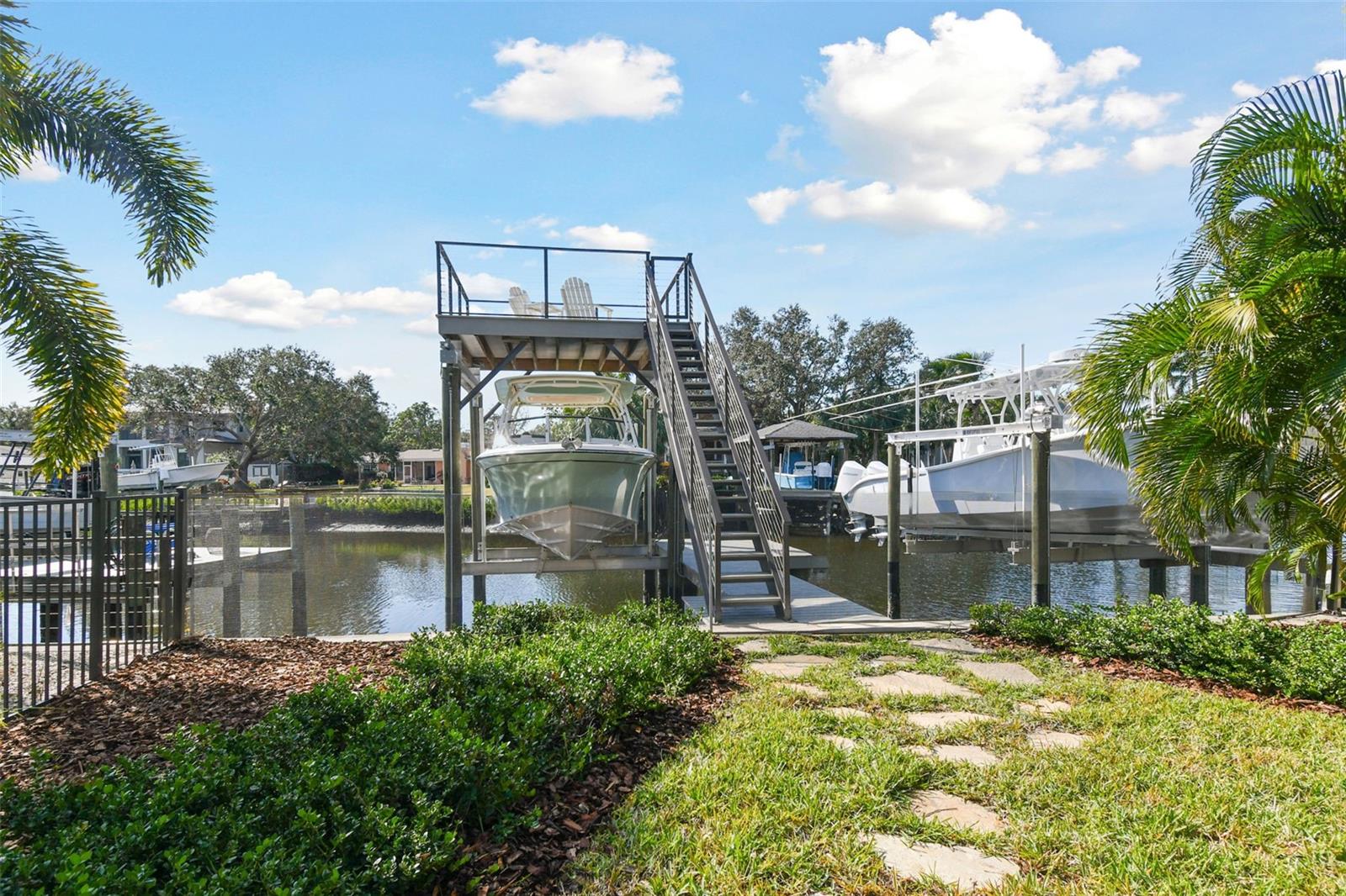 Stone pathway leads to two-story dock with 13K boat lift