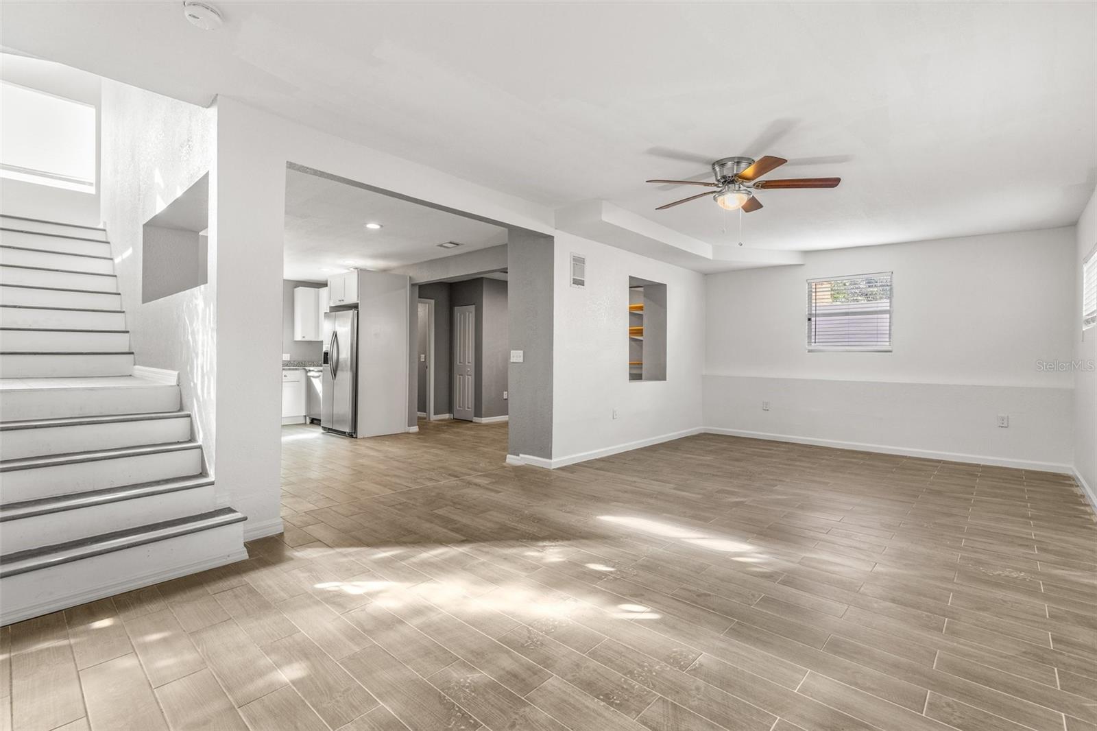 Spacious living room with ceiling fan leads into a kitchen with dining area (or office space) with full bathroom on this floor.