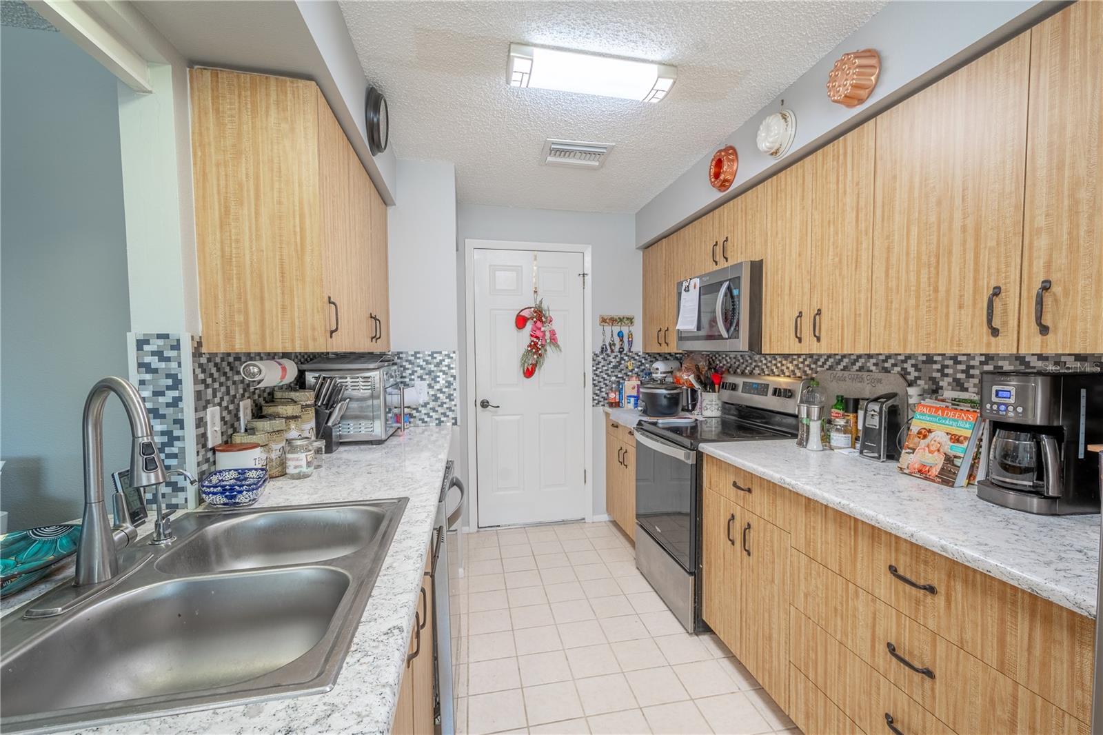 The kitchen features a stylish tile backsplash, ceramic tile floor and convenient access to the garage.