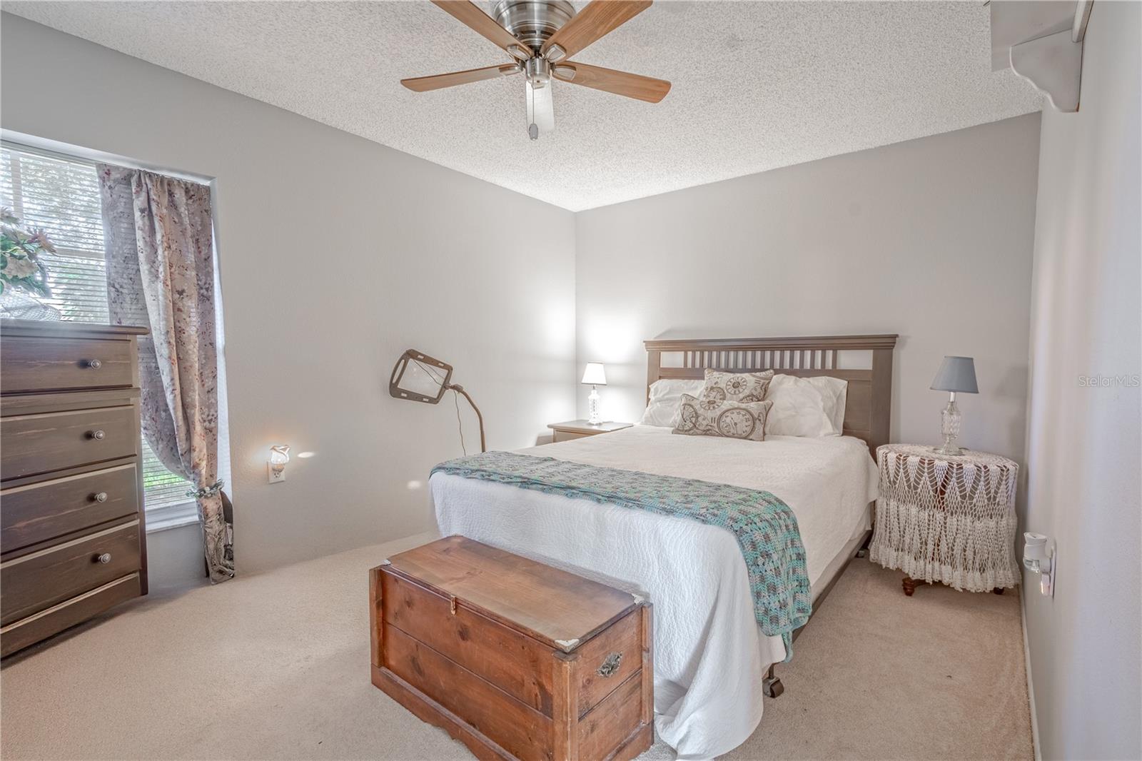 The 2nd bedroom features neutral tones, carpet, and ceiling fan with light kit.