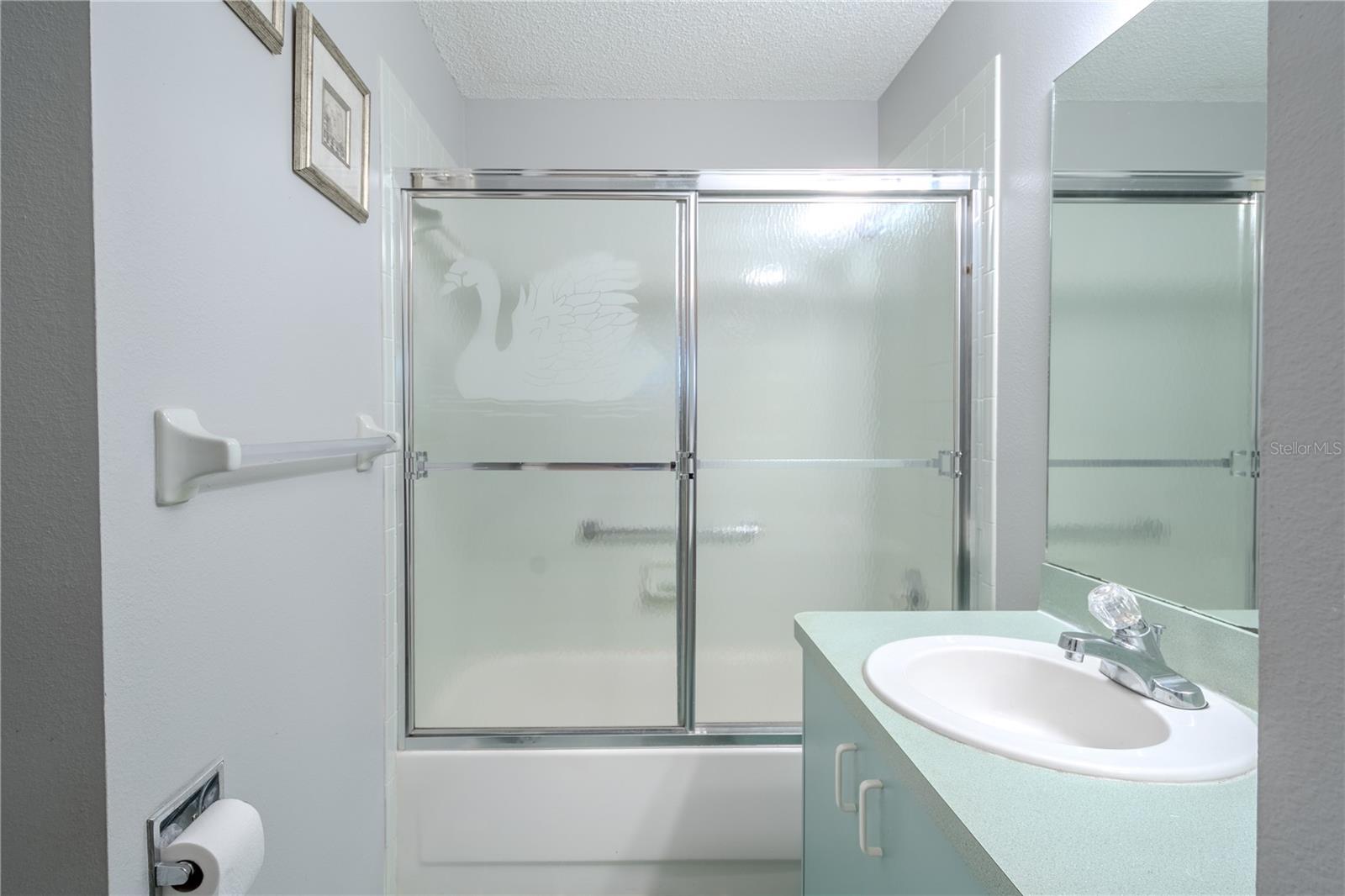 The 2nd bathroom feature a mirrored vanity with storage, ceramic tile floor and a tub with shower.