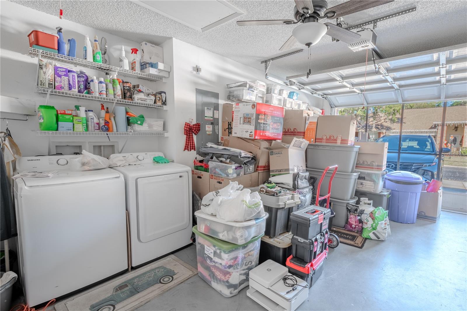 The garage features a washer and dryer with shelving, a ceiling fan with light kit, a screen door and electric door opener.