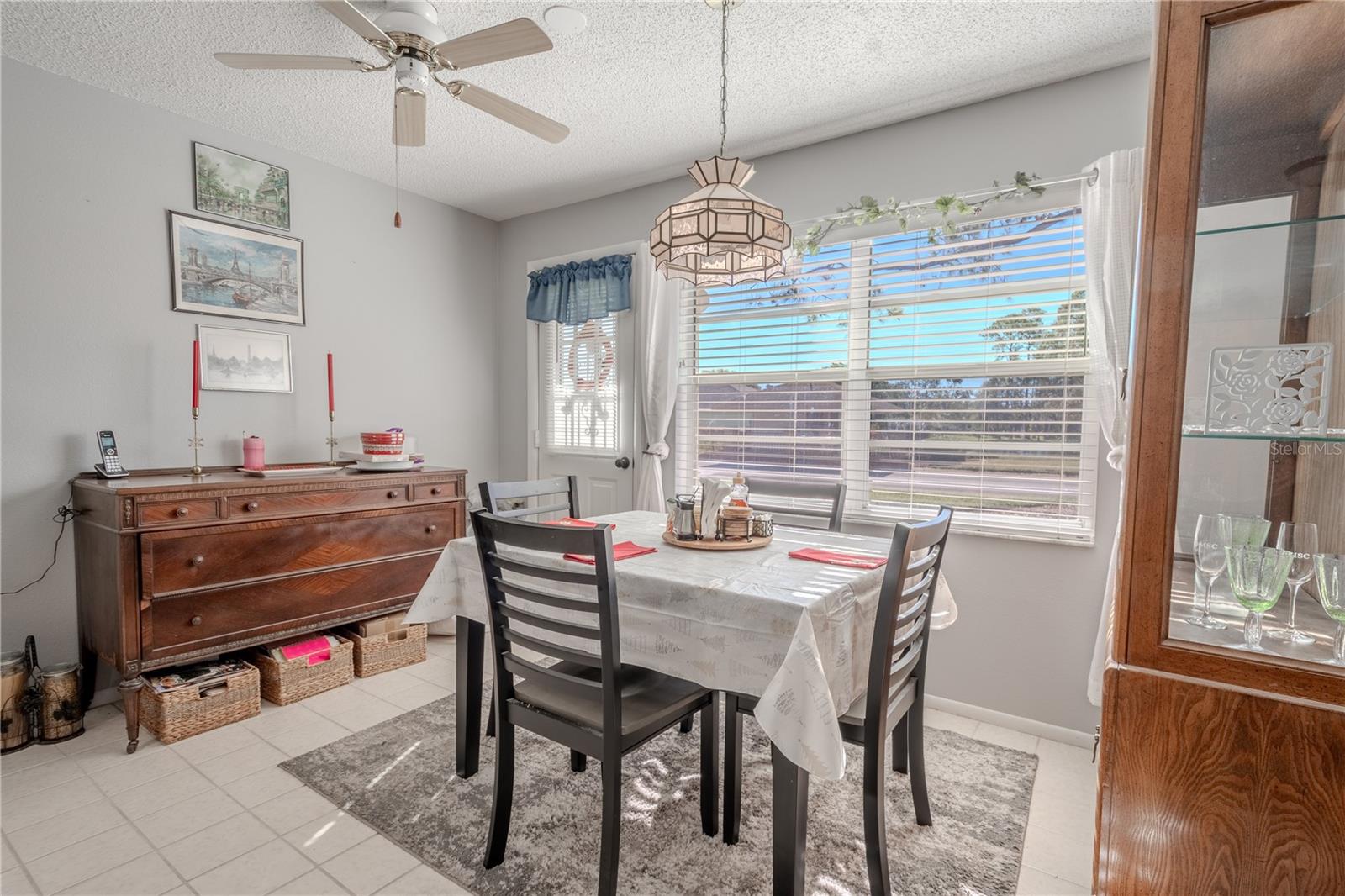 The kitchen features a cozy dinette with ceiling fan, Tiffany inspired pendant light and ceramic tile flooring.