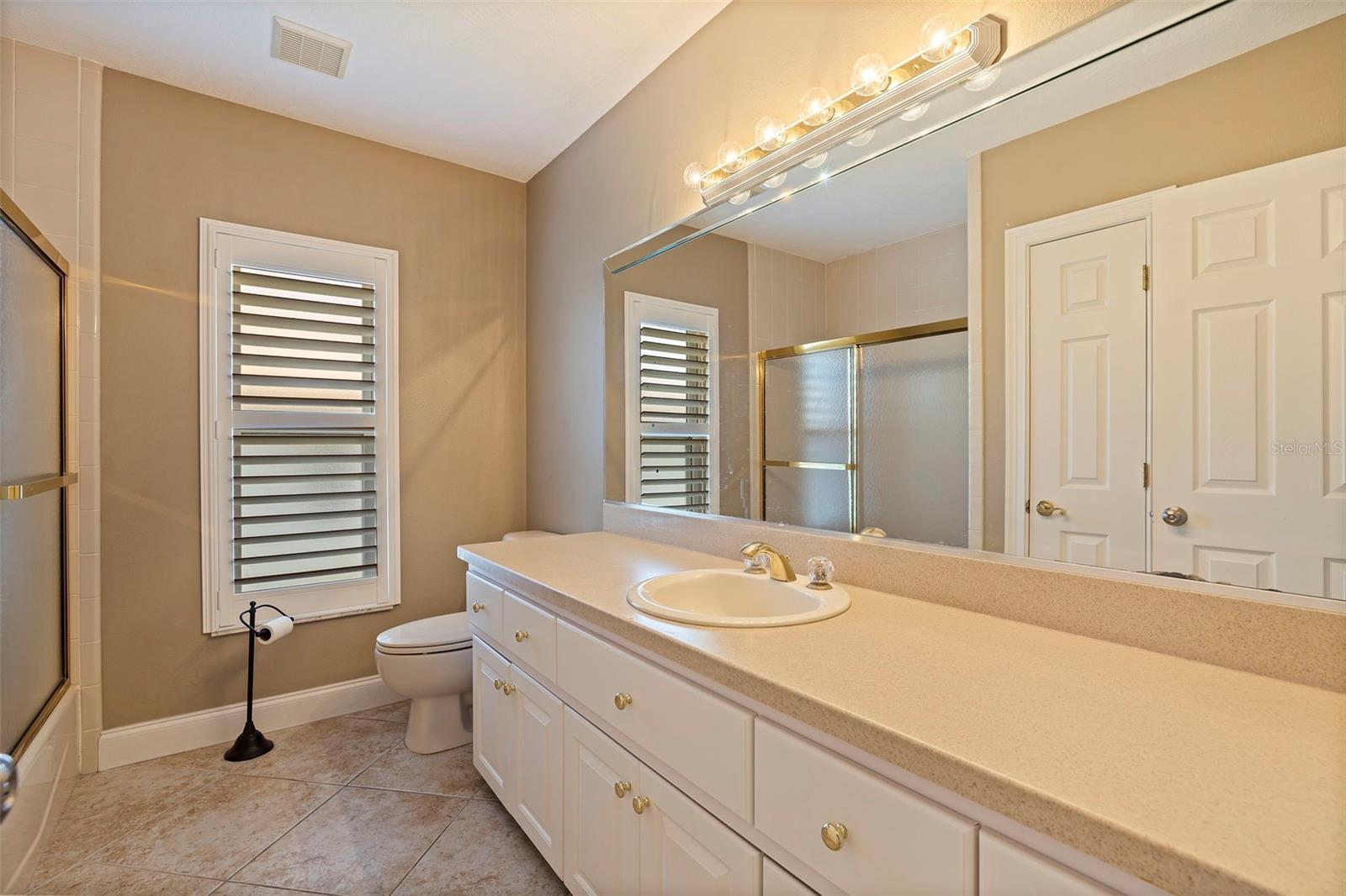 Spacious 2nd bathroom with Corian countertop and plantation shutters