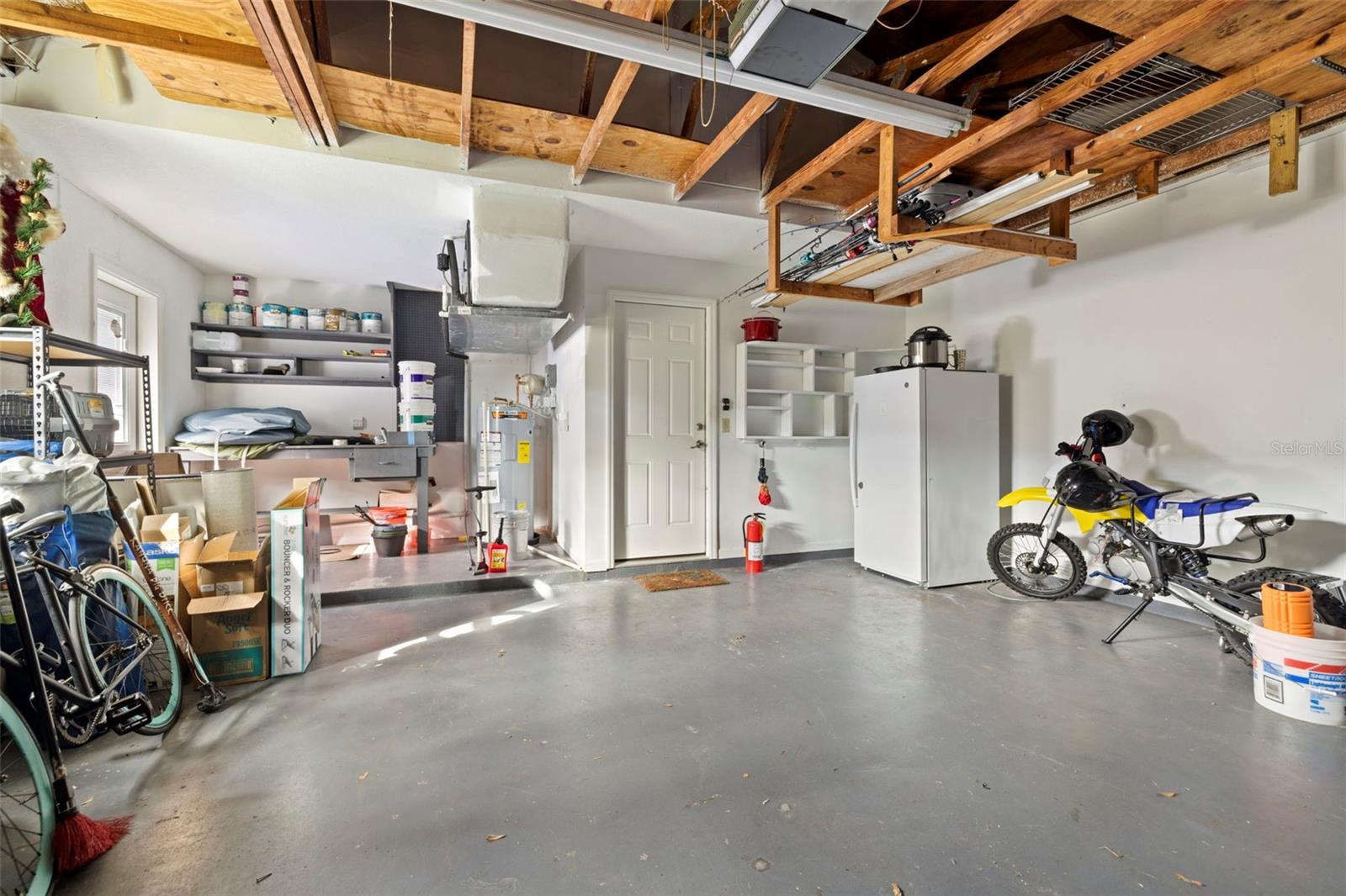 Oversized 2 car garage with built-in work bench, shelving, deep freezer and upper storage