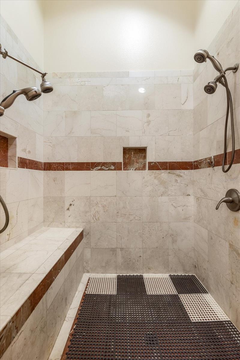 Walk-in Primary Shower with marble floors, walls, and double shower heads