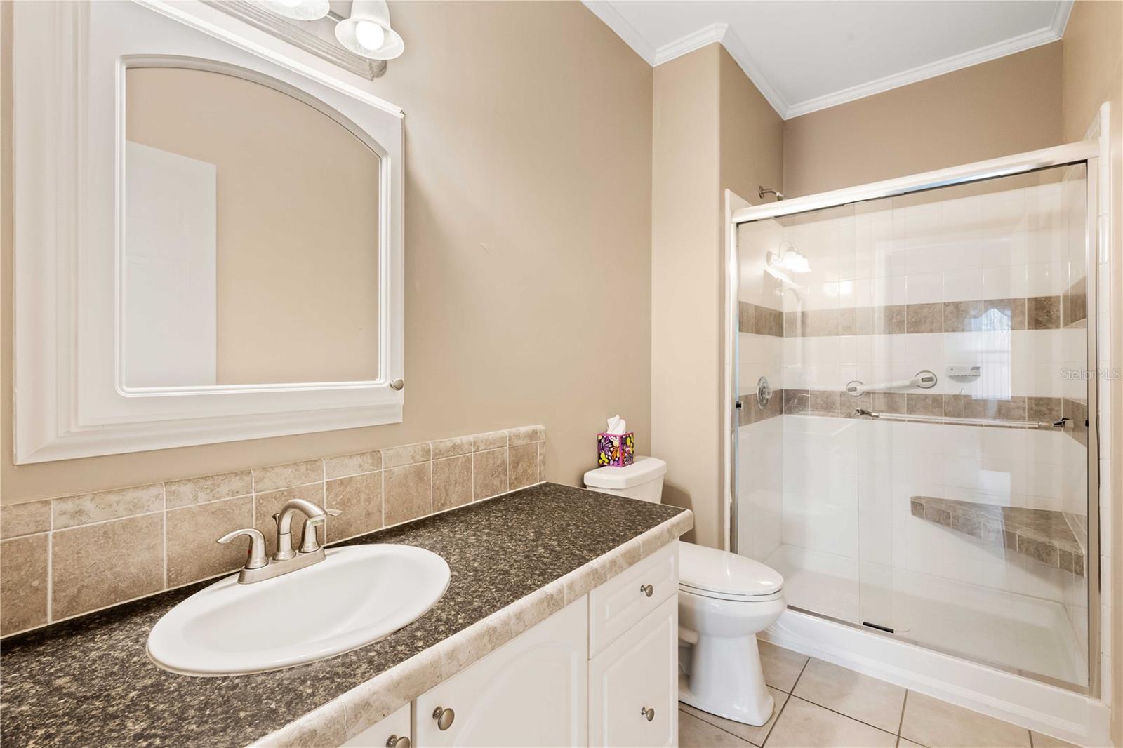 Guest bathroom has updated step-in shower with custom tile work.