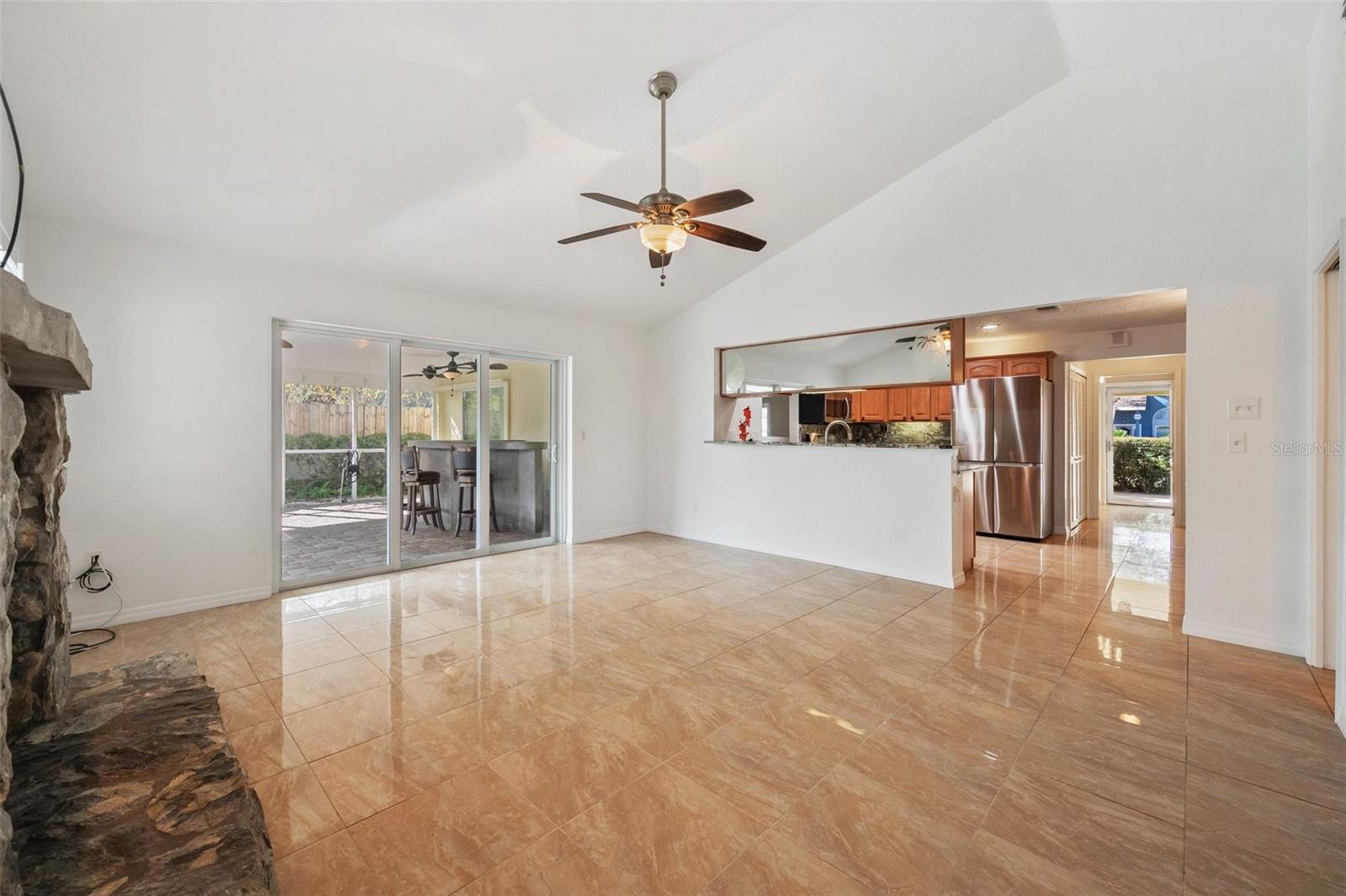 Family room looking out to the bar and pool. Bar has sink and refrigerator. 3 ceiling fans in bar area.