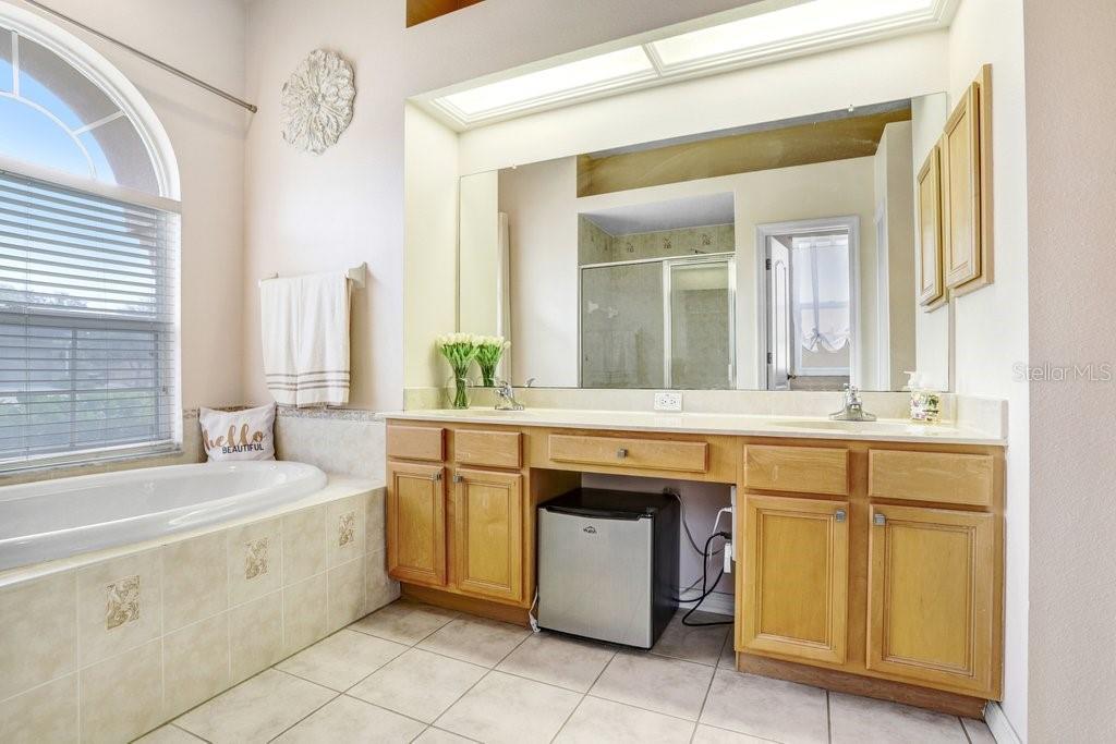 Primary suite with view to the the bathroom with dual sinks, walk-in shower and tub